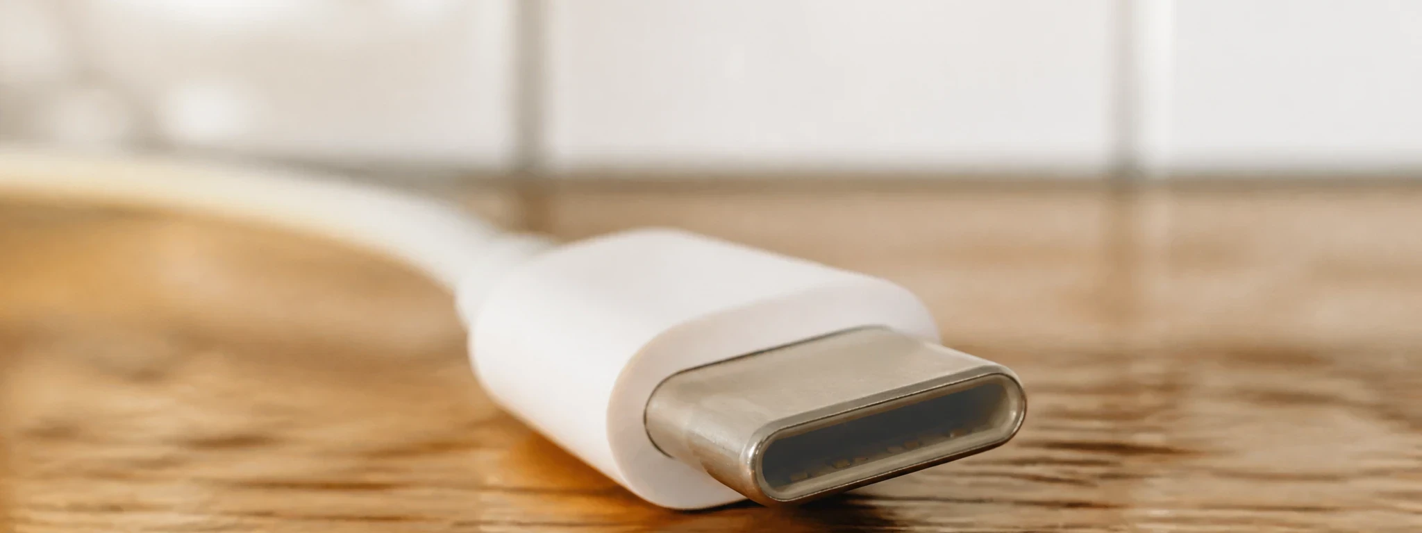 Gros plan sur l'extrémité d'un câble USB-C posé sur un plan de travail en bois