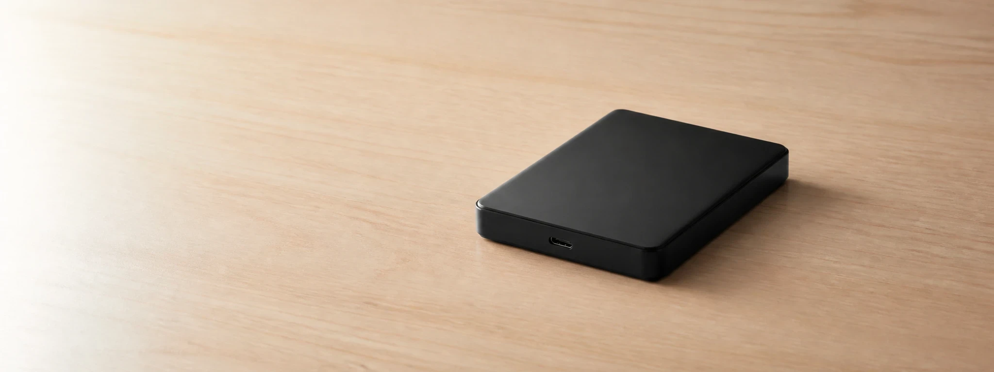 Un disque dur externe seul au centre d'un bureau clair