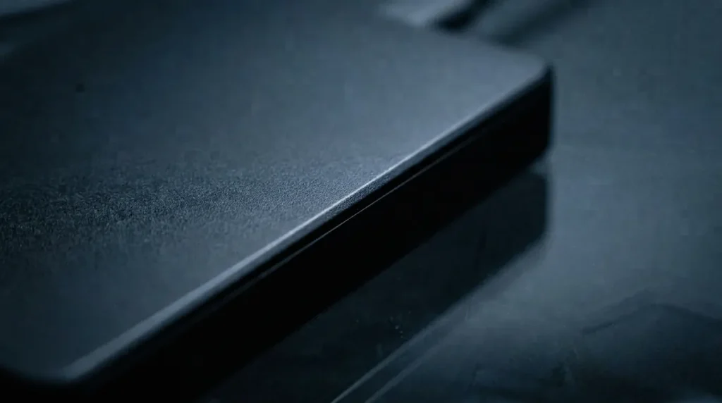 Vue macro sur l'angle d'un boîtier de disque dur externe posé sur du verre sombre
