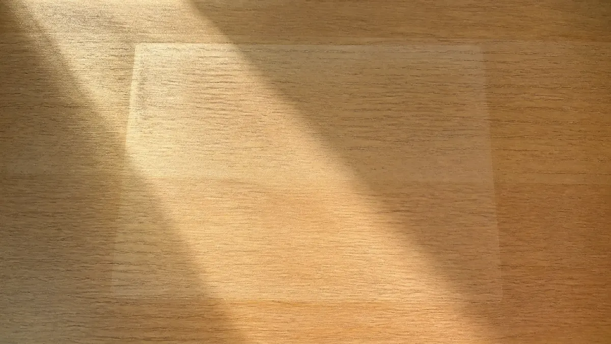 La surface d'un bureau en bois clair, avec la trace laissée par un objet posé longtemps au même endroit