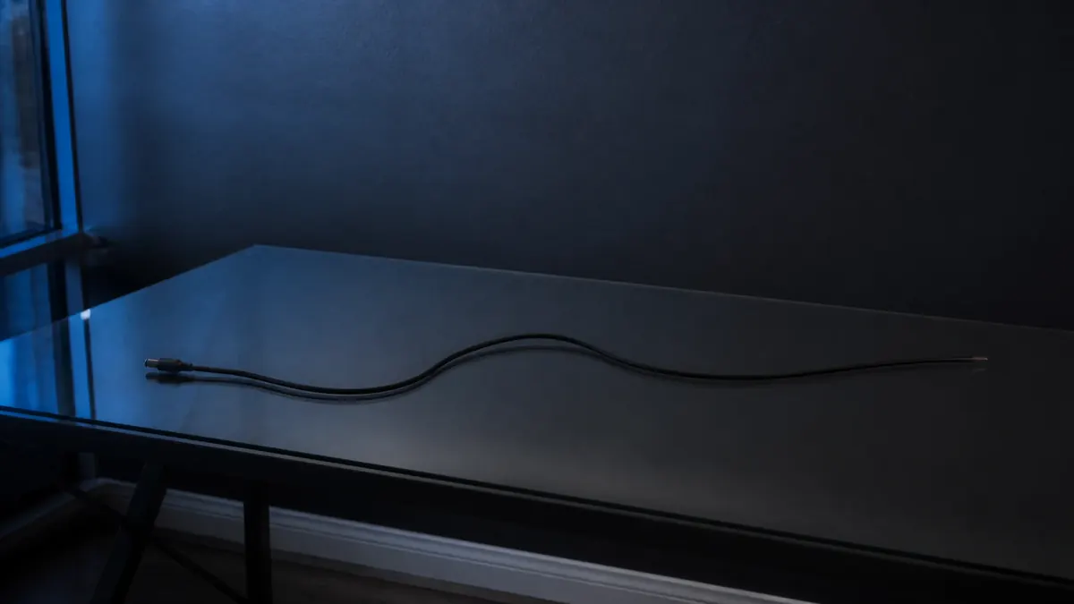 Un bureau en verre vide, traversé par un seul câble débranché